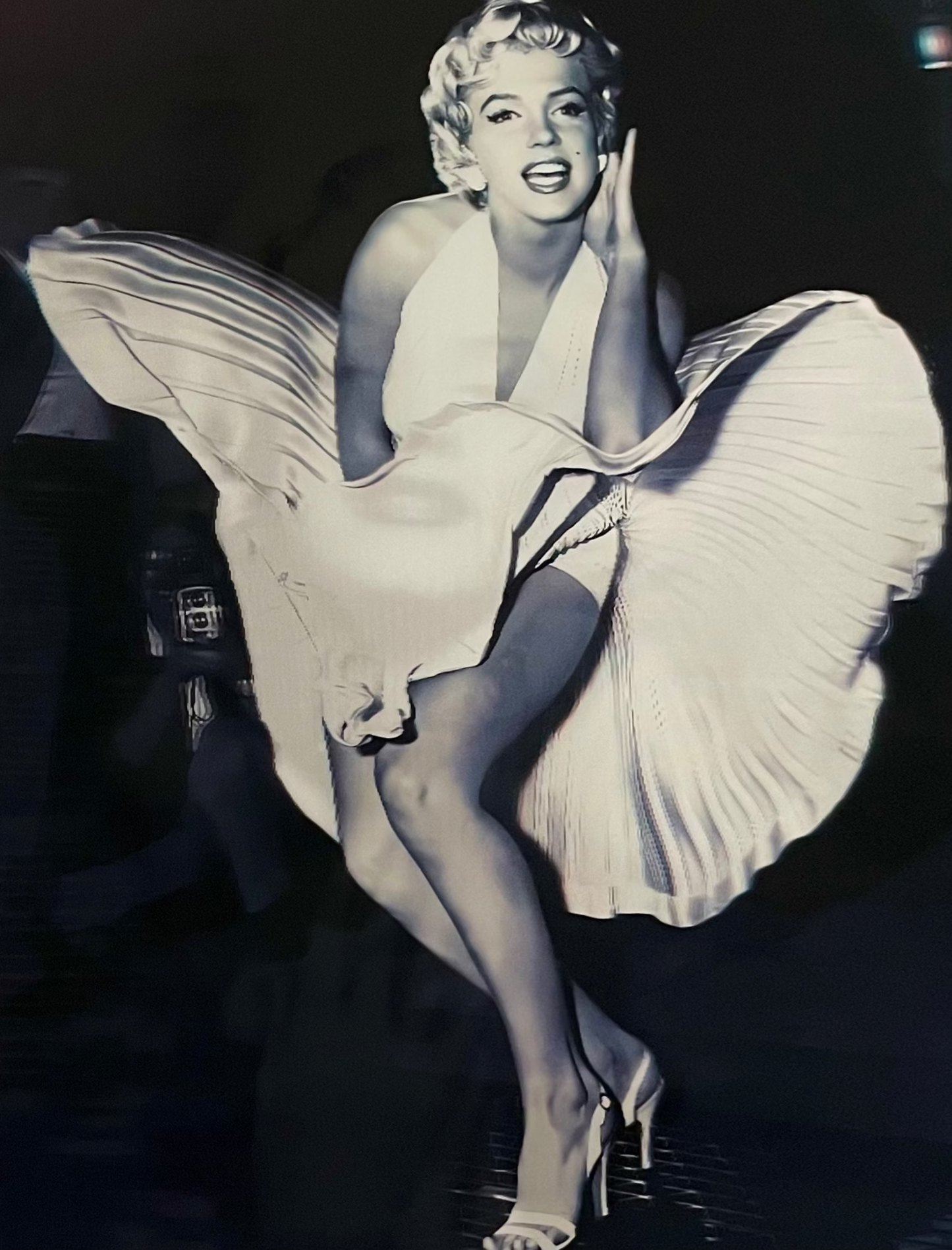 Black and white image of famous actress Marilyn Monroe in a flowing dress sitting on a chair.